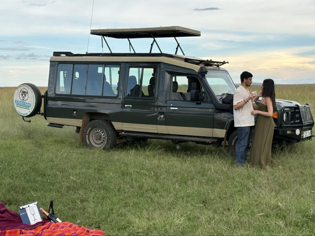 A romantic couple holding drinks next to a vehicle on serengeti honeymoon safari packages.