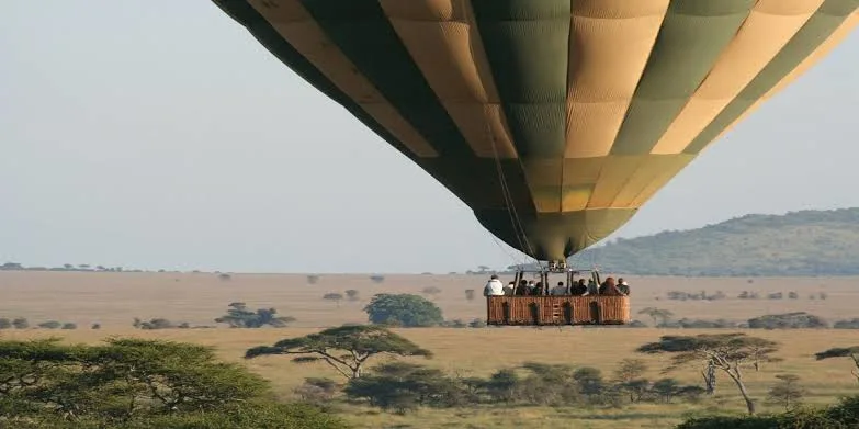 A hot air balloon drifting low over the savanna plains during Serengeti safari activities.
