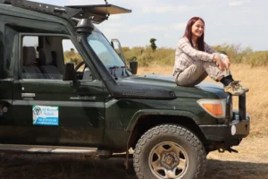 A woman smiling while sitting on a safari vehicle during serengeti wildlife safari packages.