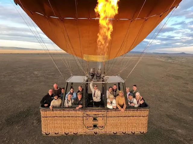 Tourists inside a hot air balloon basket during a serengeti balloon safari package.