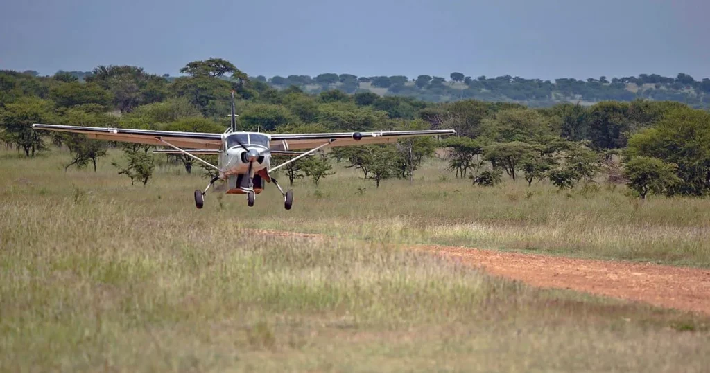 Safari bush plane landing on a dirt airstrip for your Serengeti safari booking.