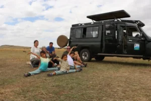 A family posing playfully by a vehicle during their serengeti family safari packages.